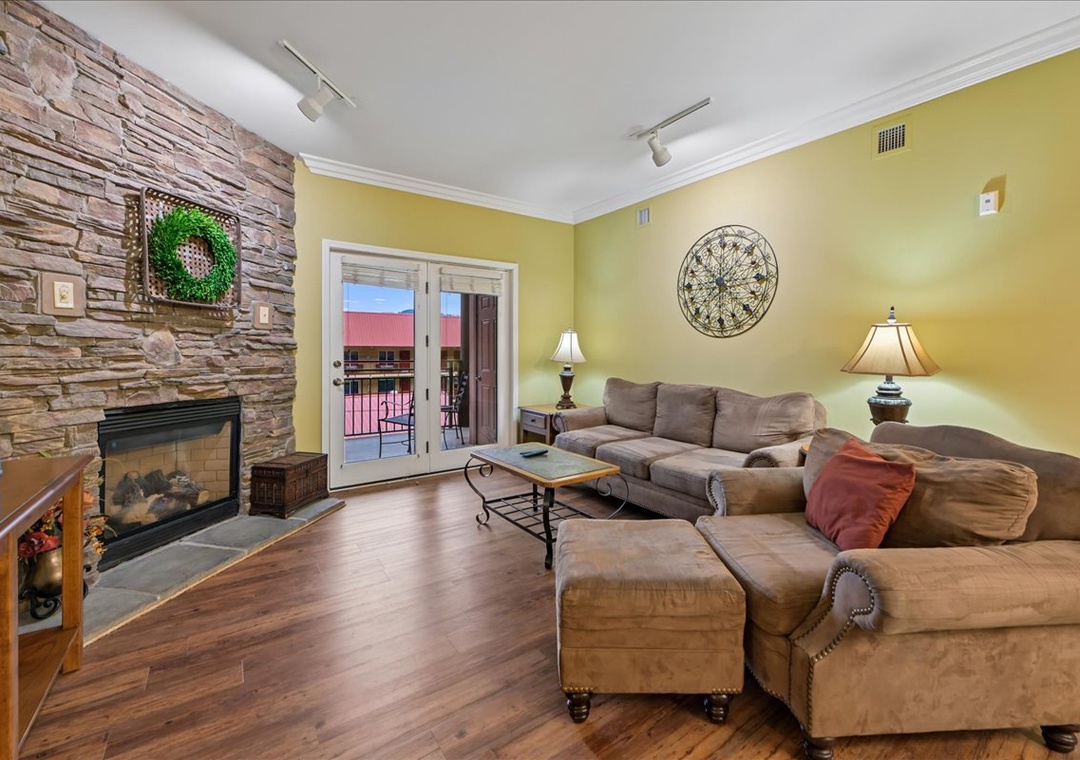 Relax in your spacious living room featuring cozy sectional seating, elegant fireplace, and private balcony access for perfect evenings.