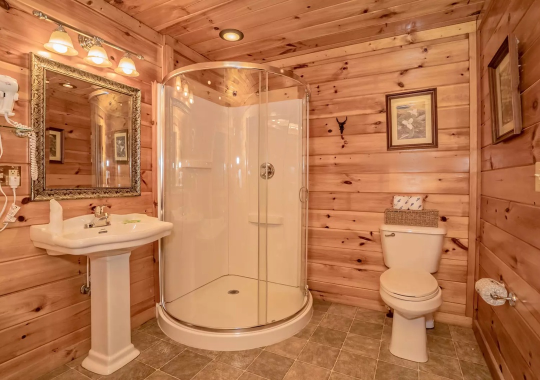 Step into your private rustic retreat with warm cedar walls, spacious glass shower, and elegant touches for a truly relaxing experience.