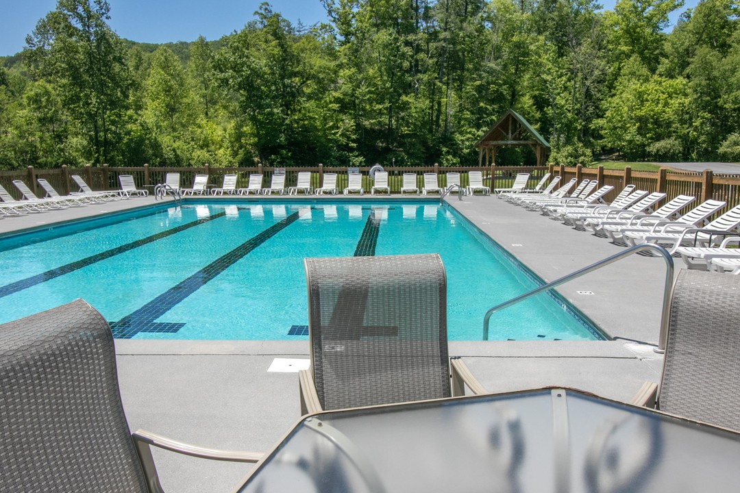 A sparkling outdoor pool surrounded by lush mountain forest awaits your arrival. Rows of lounge chairs invite relaxing afternoons under the canopy of trees.