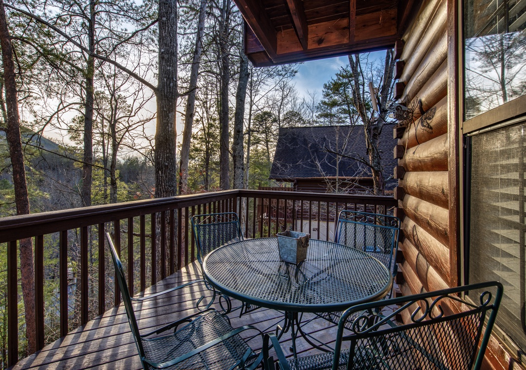 Your private balcony offers peaceful forest views with a charming table for two, perfect for morning coffee surrounded by tall trees.