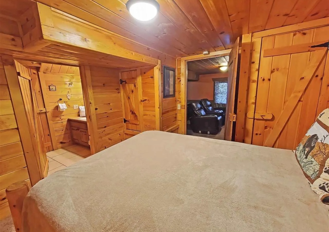 Cozy up in this warm log cabin bedroom with rustic wood walls and open access to your living area.