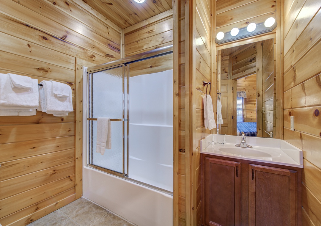 Step into a bathroom that blends rustic charm with modern comfort, featuring warm wood paneling and fresh towels waiting for you after a relaxing soak.