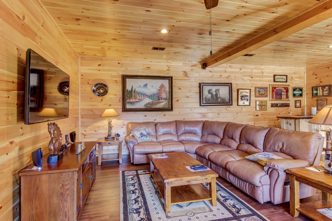 Settle into the plush leather sectional in your cozy living room, where exposed wood beams and rustic charm make every moment feel like a mountain retreat.