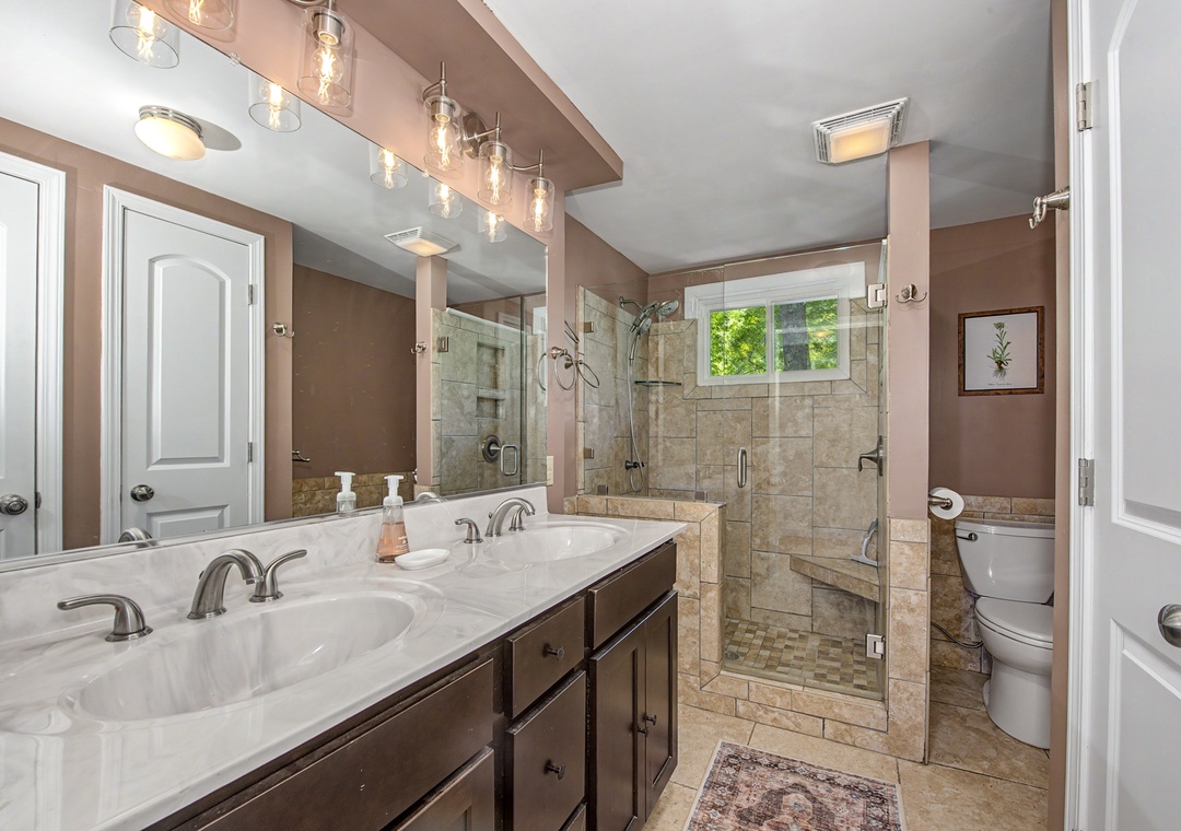 Step into your elegant ensuite, where soft lighting and a spacious walk-in shower with classic tile await your morning refresh.