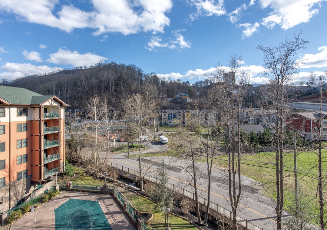 Mountain resort community with nearby residential buildings, roads, and forested hillsides creating a peaceful vacation destination setting.