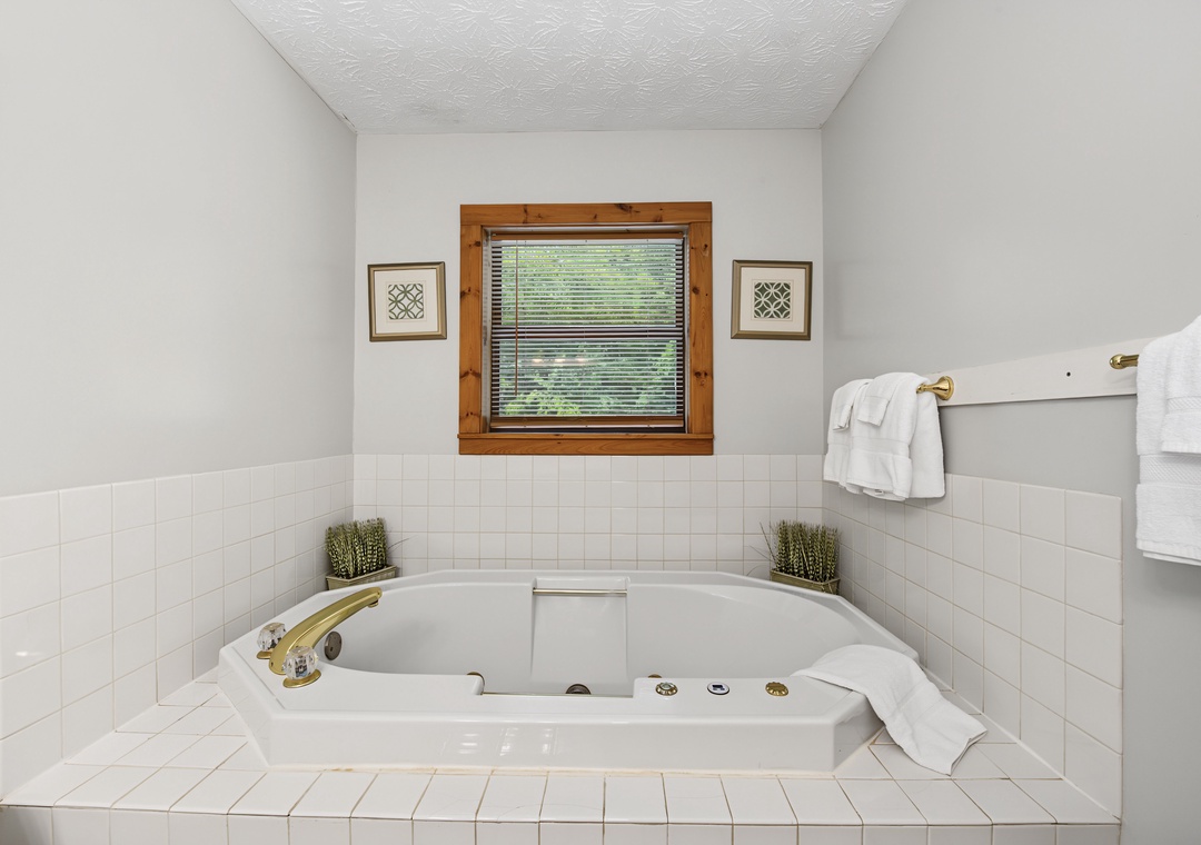 Sink into your private jetted tub surrounded by crisp white tile, soft towels within reach, and a tranquil garden view—relaxation awaits.