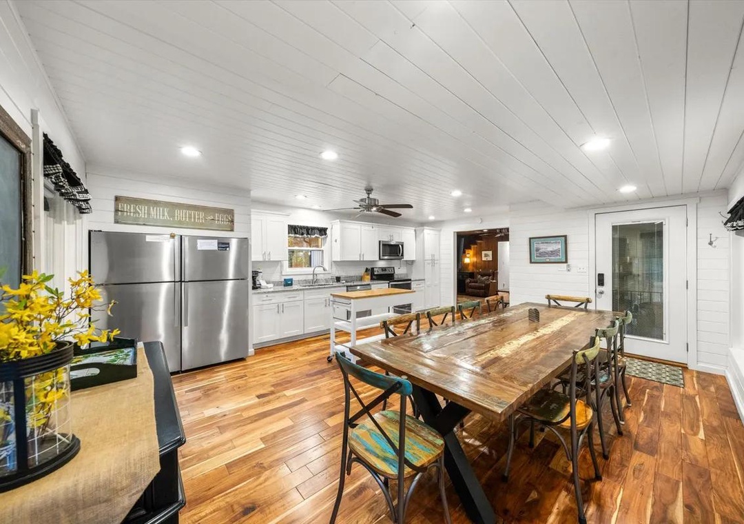 Bright, welcoming space where rustic charm meets modern comfort. Farmhouse-style dining table, fully equipped kitchen, and warm wood floors create an inviting atmosphere perfect for gatherings.