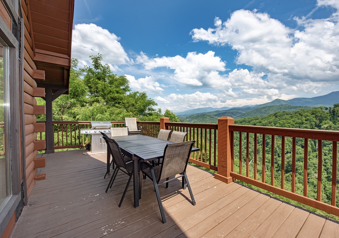 Spacious mountain cabin deck features sweeping views of forested peaks, complete with outdoor dining for six and a built-in BBQ grill for memorable al fresco meals.