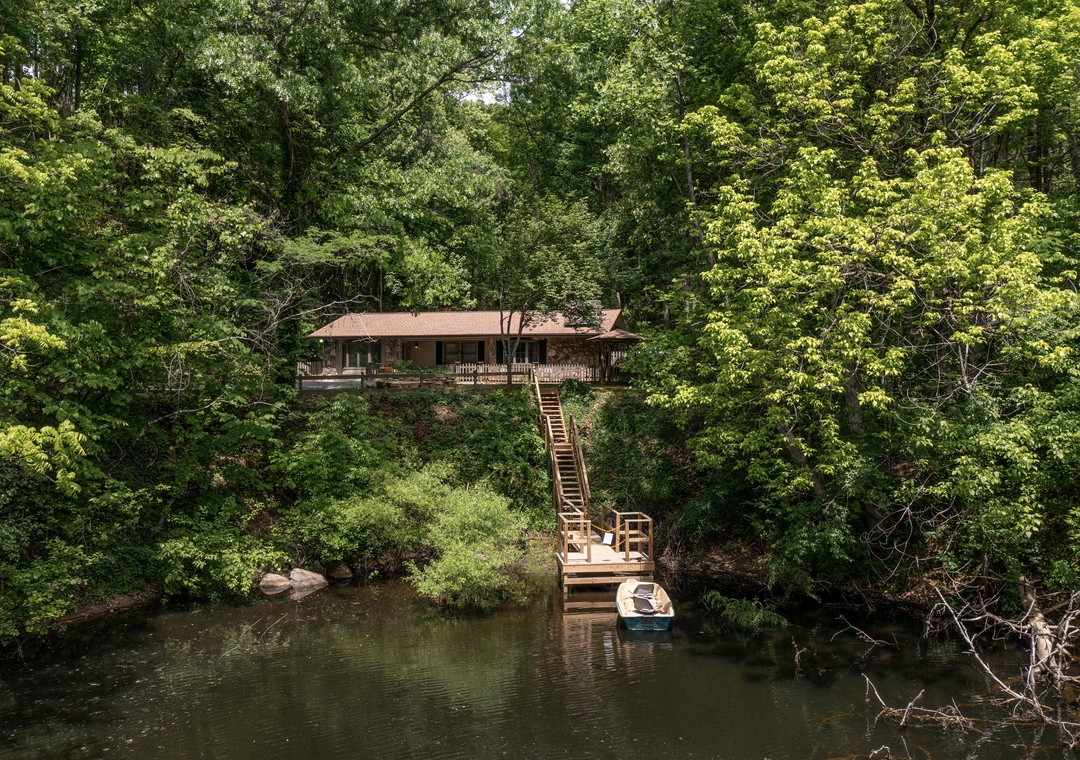 Secluded waterfront retreat nestled in lush forest with private dock and boat access, offering peaceful natural surroundings and direct water access for a tranquil getaway.