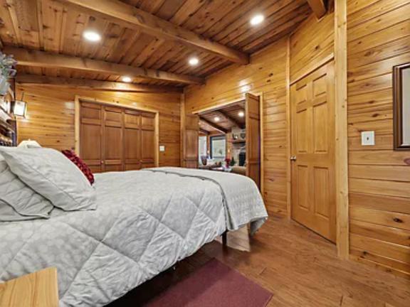 Unwind in your cozy cabin bedroom, where rustic wood beams and warm natural light create a peaceful mountain retreat for restful nights.