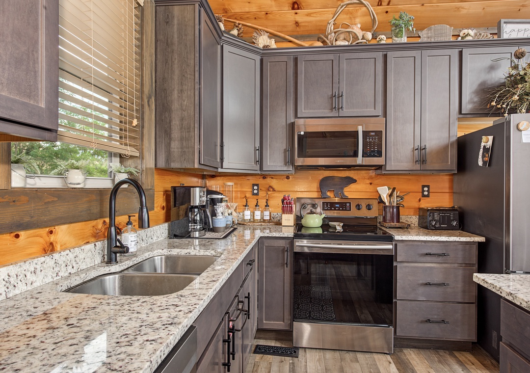 Your fully equipped kitchen features granite countertops, stainless steel appliances, and warm wood accents—perfect for preparing meals while soaking in the cozy cabin atmosphere.