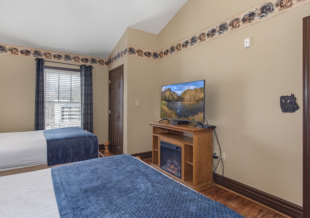 Relax in your cozy bedroom with twin beds, flat-screen TV, and warming fireplace creating the perfect retreat.