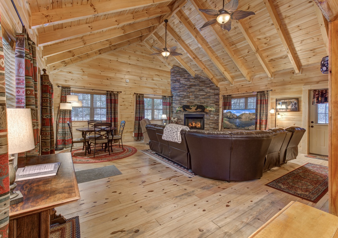 Cozy up in this rustic living room where warm wood beams and a crackling stone fireplace create your perfect mountain retreat.