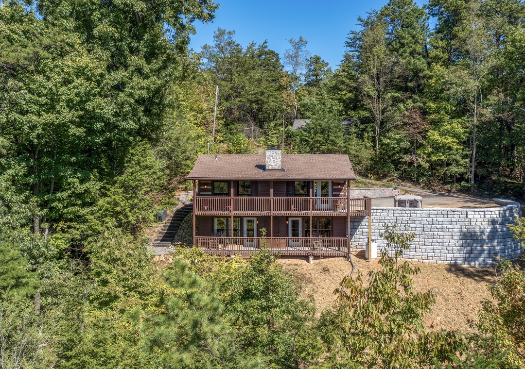 This charming cabin retreat sits nestled among towering trees, offering a peaceful woodland escape with spacious decks and rustic character.