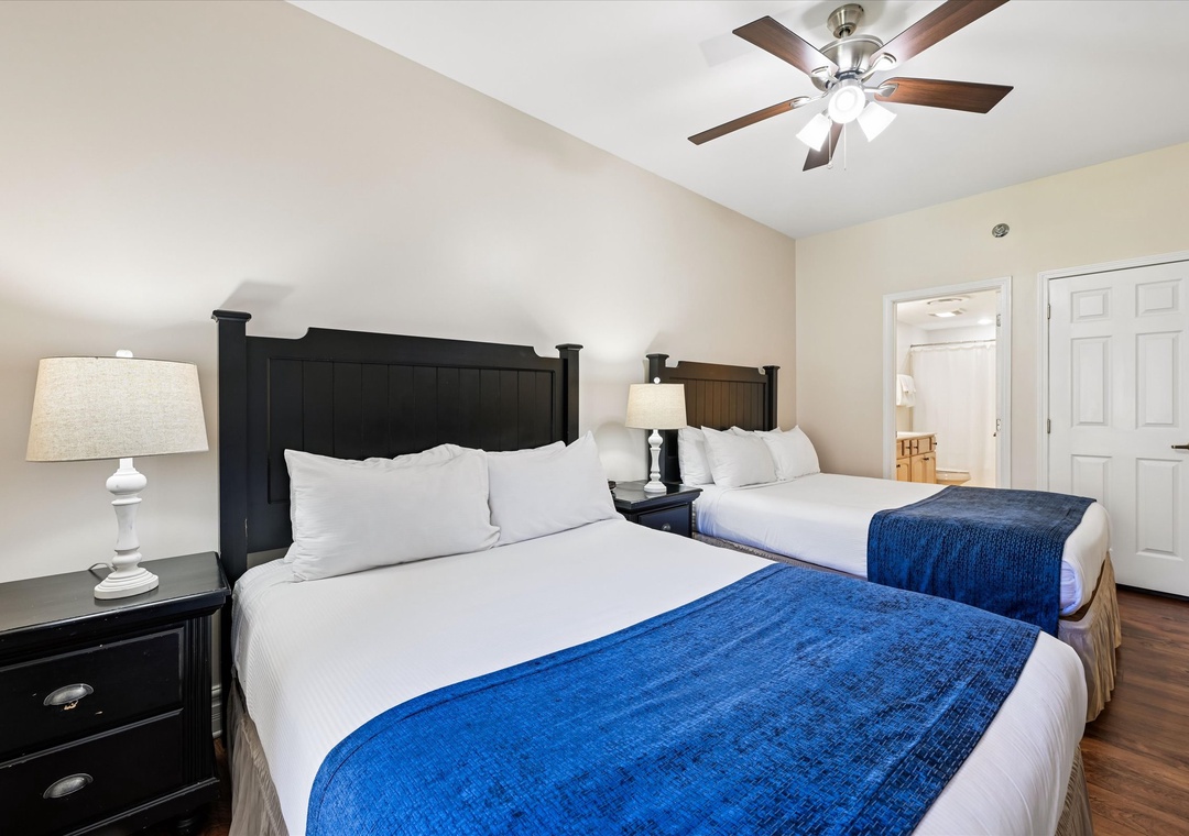 Rest peacefully in your spacious bedroom featuring two comfortable beds with crisp white linens and vibrant blue accents.
