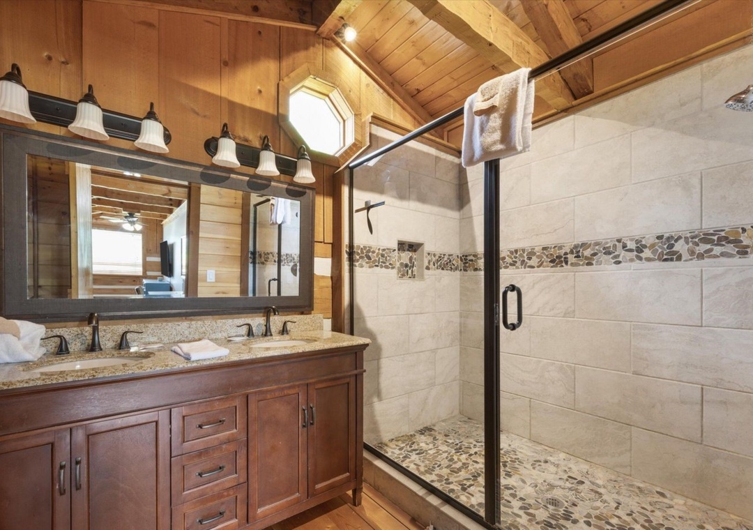 Your rustic bathroom blends mountain charm with modern luxury—spacious shower, granite vanity, and warm wood create your perfect retreat.