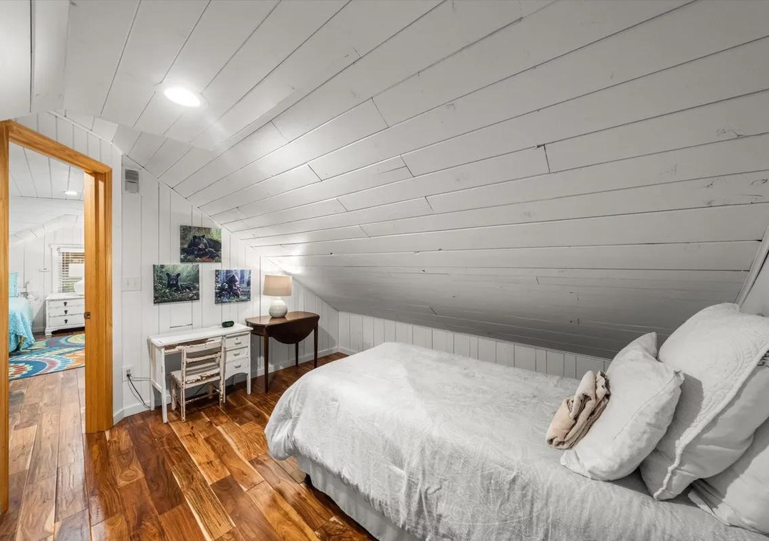Drift off under the sloped ceiling in this cozy bedroom with gleaming wood floors and crisp white linens waiting for your arrival.