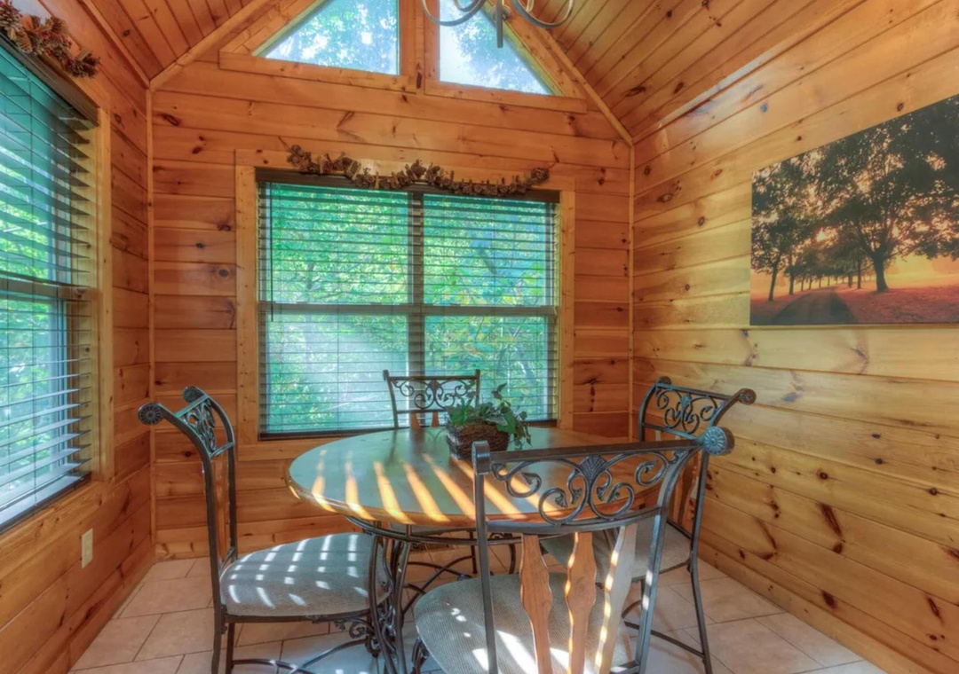 Sunlight streams through tall windows into your cozy dining nook, where warm wood walls and vaulted ceilings create a peaceful retreat for morning coffee or evening meals with loved ones.