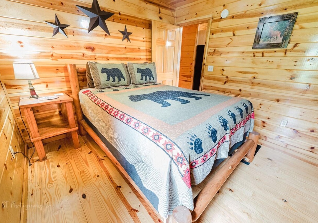 Your rustic retreat features warm pine walls, charming bear-themed bedding, and a cozy platform bed beneath decorative metal stars—perfect for unwinding after a day of mountain adventures.