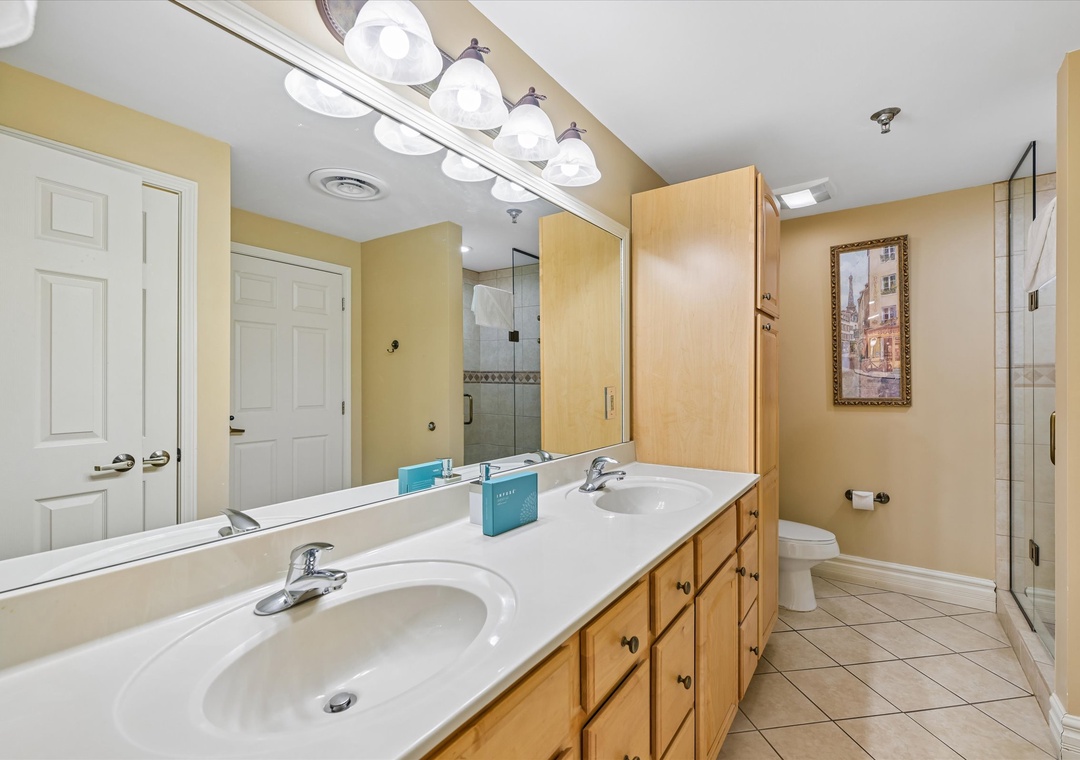 Your spacious master bathroom features dual sinks, warm wood vanity, and luxurious glass shower for ultimate comfort.