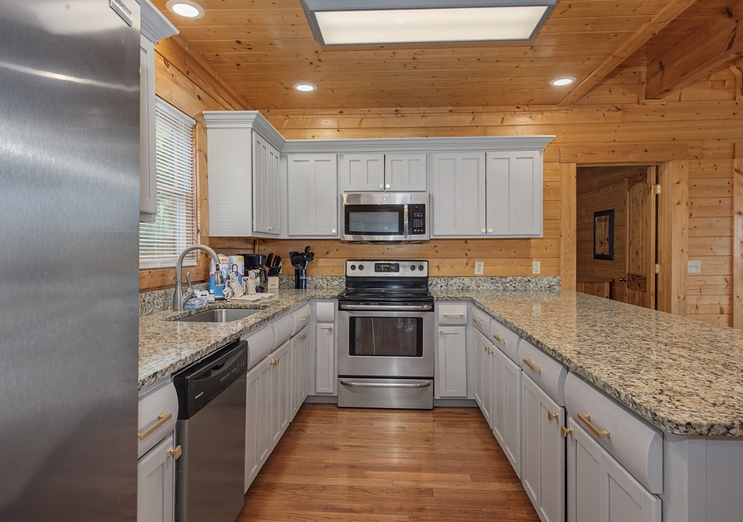 Your fully equipped kitchen awaits with granite counters, stainless steel appliances, and warm wood beams overhead for memorable meal prep.