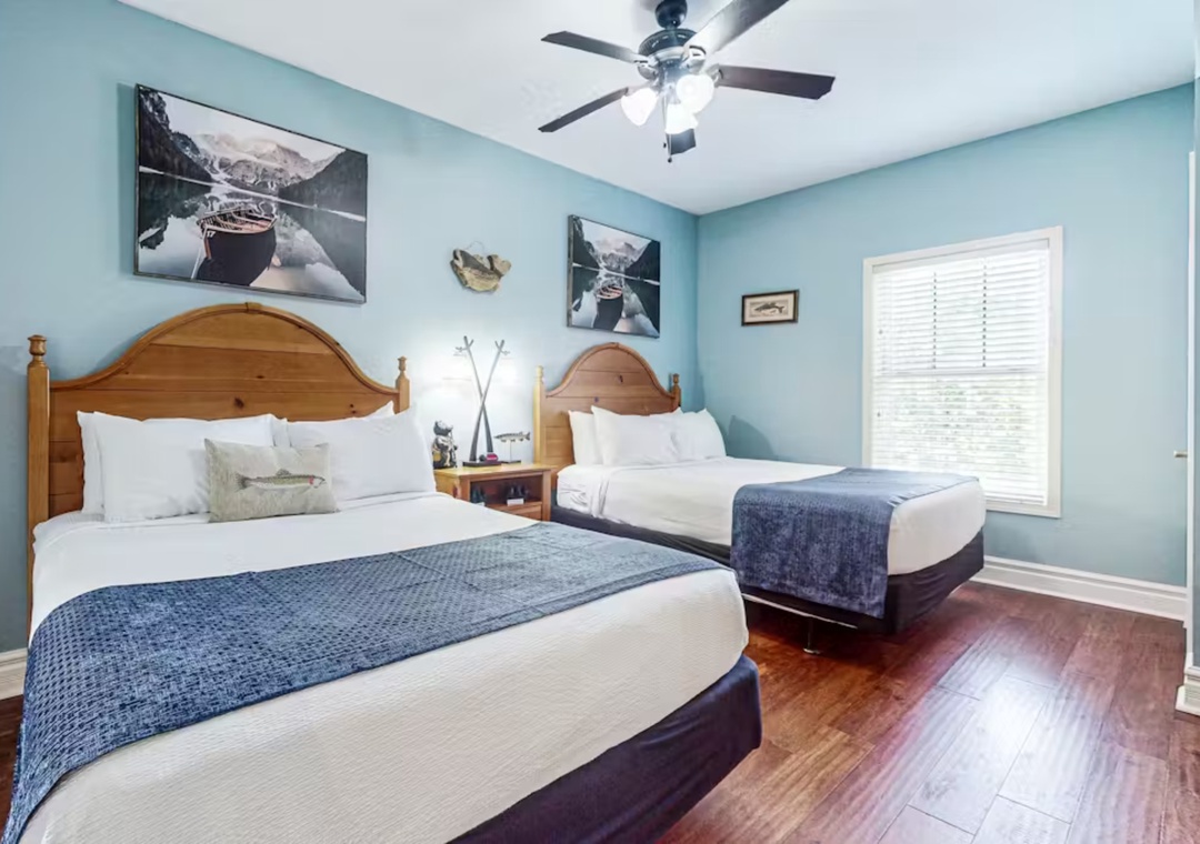 Relax in this peaceful bedroom featuring two comfortable beds with crisp linens and charming nautical artwork adorning the calming blue walls.