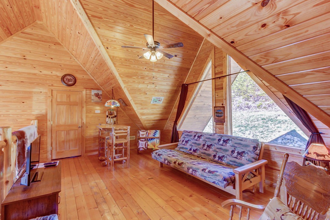 Unwind in your cozy A-frame retreat with soaring pine ceilings and large windows framing peaceful forest views—your mountain escape awaits.