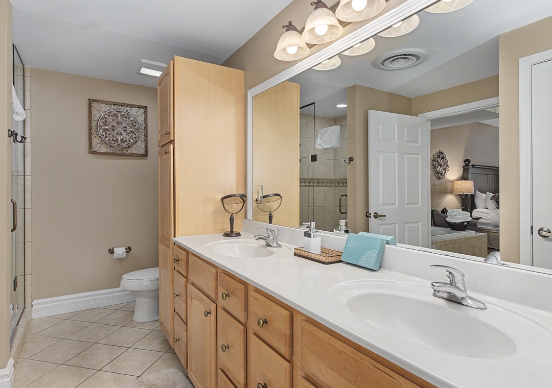 Refresh in your spacious dual-vanity bathroom with warm wood cabinetry, elegant lighting, and thoughtful amenities.
