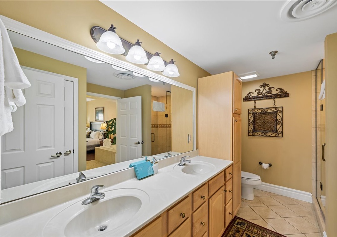 Step into your spacious bathroom featuring dual sinks, warm wood cabinetry, and elegant lighting for comfortable morning routines.
