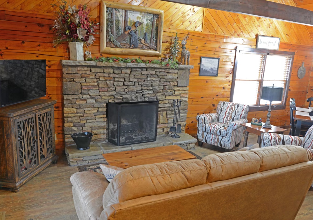 Cozy up in this rustic living room where warm wood walls and stone fireplace create the perfect cabin retreat atmosphere.