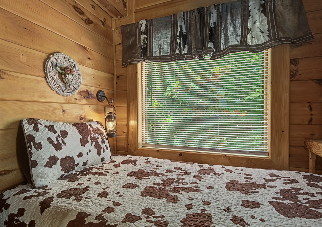 Relax in your cozy bedroom with warm wood walls, rustic charm, and a window framing lush greenery—your peaceful retreat awaits.