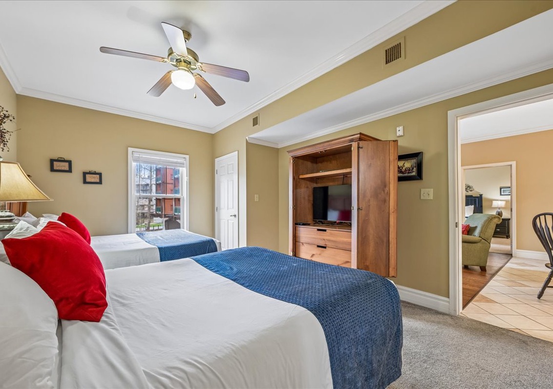 Rest easy in your spacious bedroom featuring two comfortable beds, thoughtful entertainment center, and calming decor for peaceful nights.
