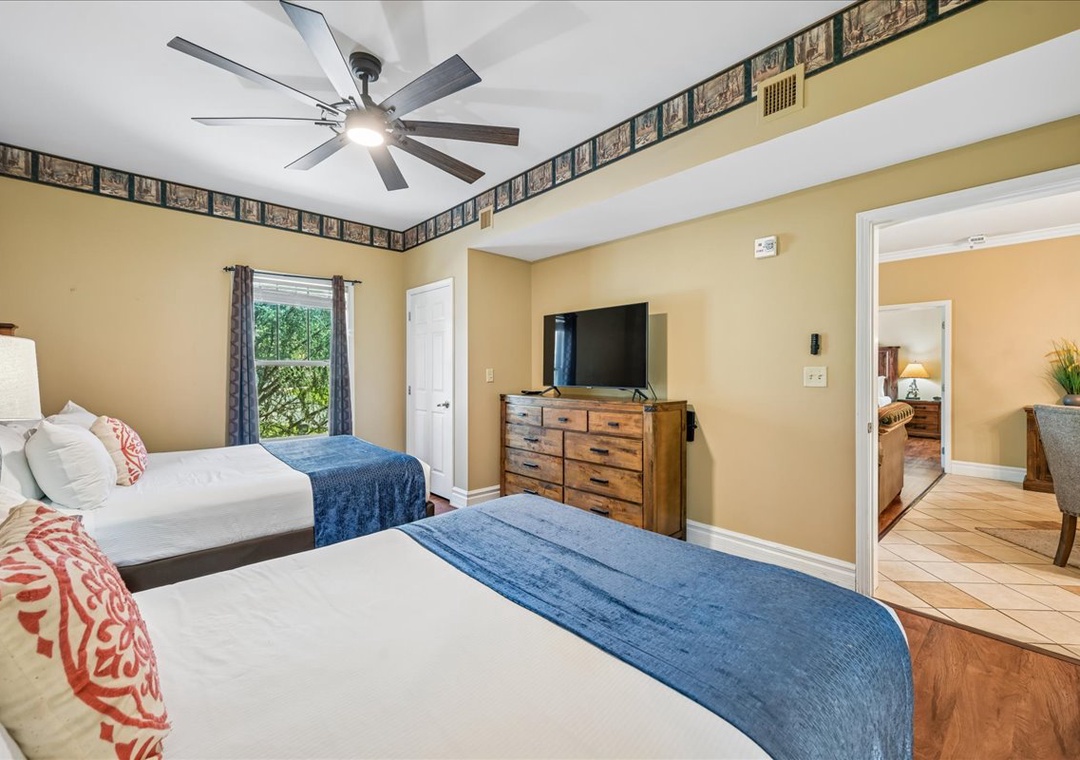 Relax in your spacious twin bedroom with ceiling fan, TV, and charming garden views through the window.