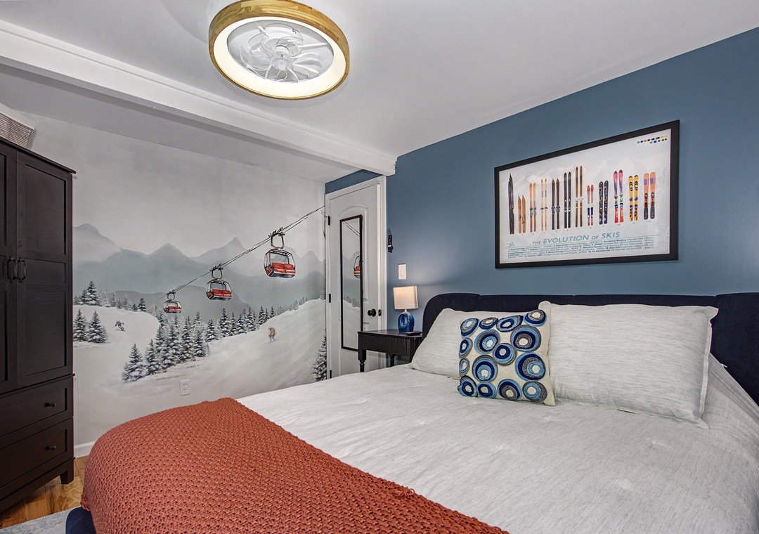 Picture yourself unwinding in this cozy bedroom, where a ski slope mural and stylish accents create a warm alpine escape perfect for your mountain getaway.
