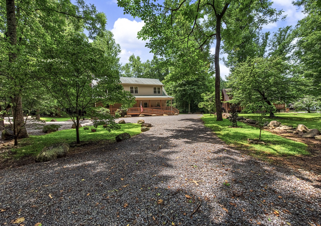 A peaceful property nestled among mature trees, featuring a gravel driveway and spacious grounds perfect for enjoying the natural surroundings.