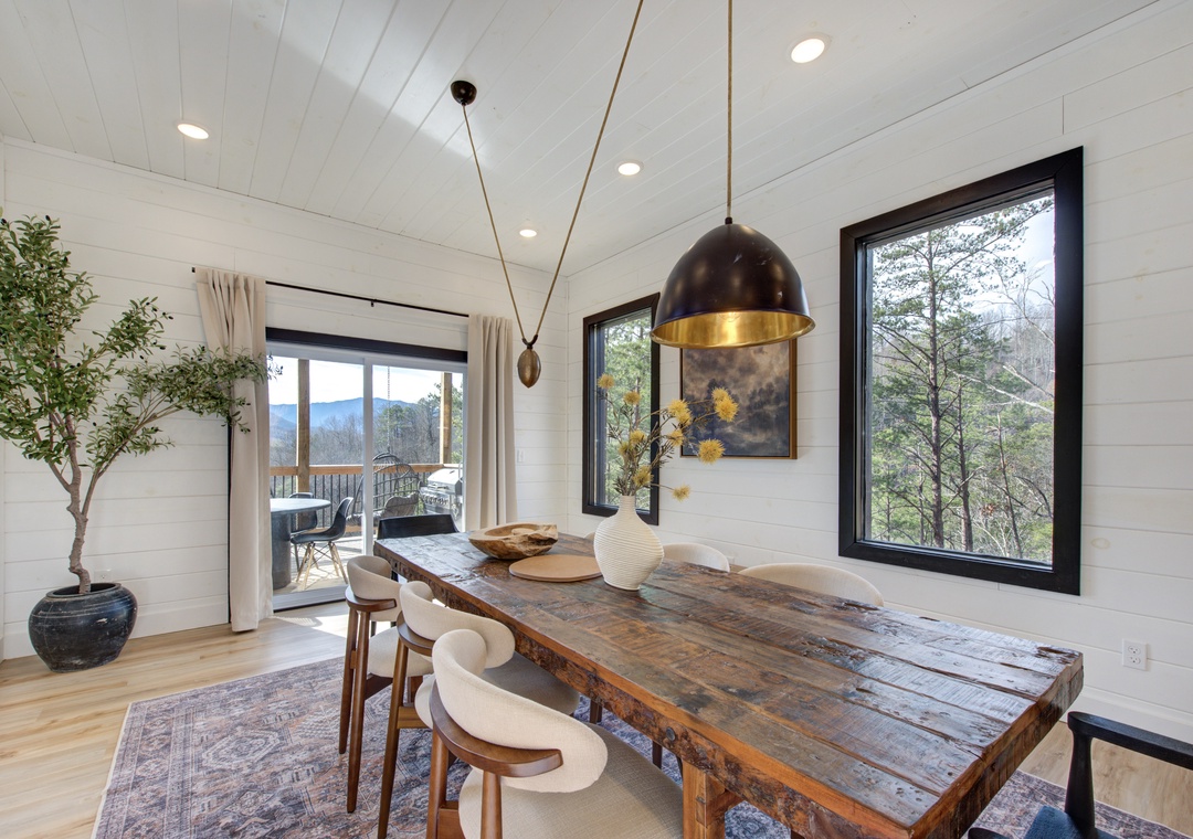 Gather around your rustic dining table where warm pendant lighting and mountain views create the perfect backdrop for memorable meals together.