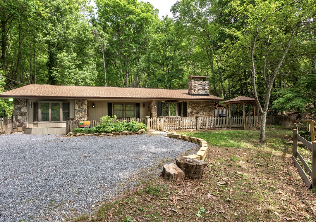 Nestled among towering hardwoods, this charming stone-accented retreat offers a private, wooded escape with ample parking and a welcoming front porch perfect for morning coffee.
