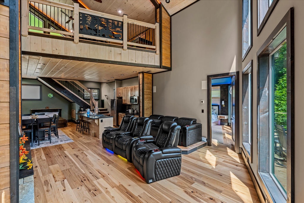 Relax in your modern loft retreat with soaring ceilings, plush theater seating, and abundant natural light streaming through floor-to-ceiling windows, all opening to a peaceful wooded escape.