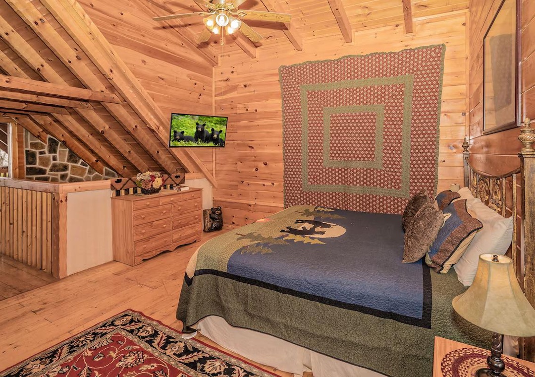 Step into your cozy loft bedroom where rustic wood beams create warmth overhead and handcrafted quilts invite restful sleep.