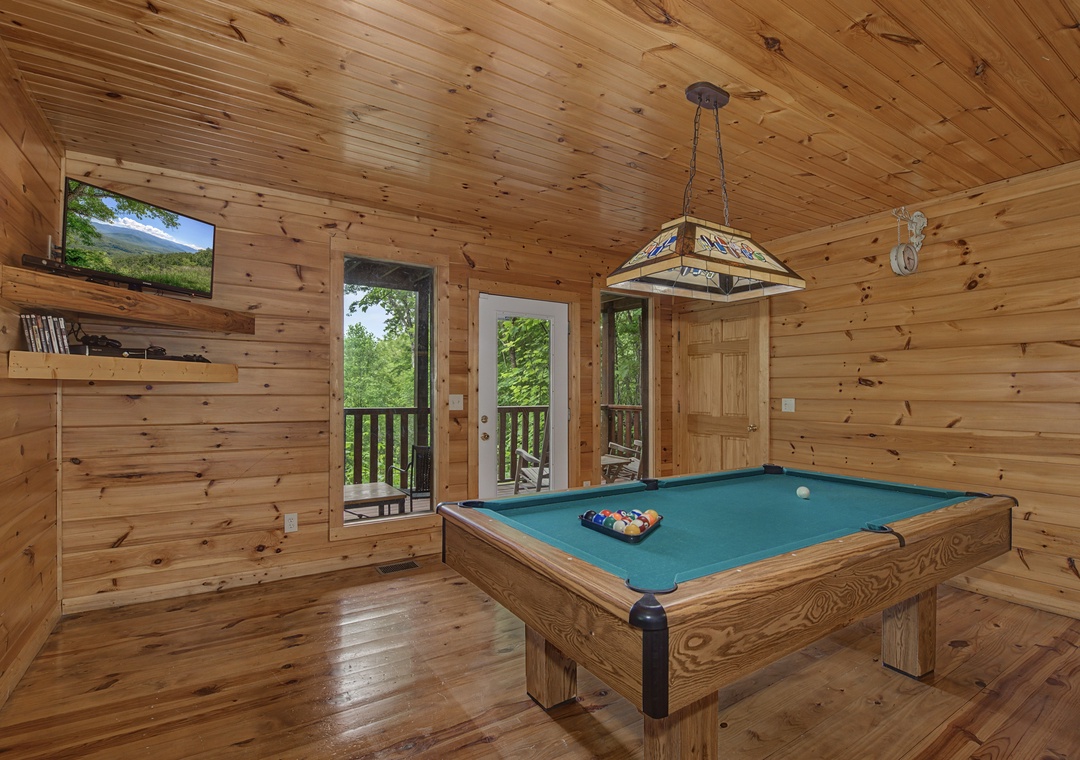 Challenge your friends to a game of pool in this warm, wood-paneled game room. Natural light pours in through balcony doors while you line up your next shot.