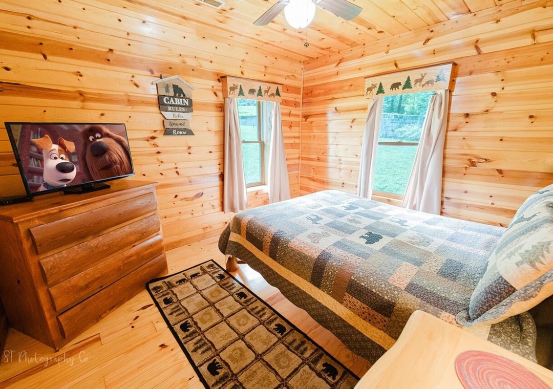 Cozy up in your rustic cabin bedroom with warm wood walls, comfy beds, and forest views framed by your windows. Your peaceful retreat awaits.