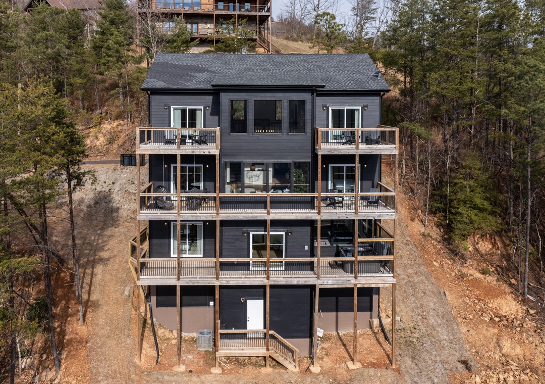 Modern mountain retreat nestled among trees with multiple private balconies for outdoor relaxation.