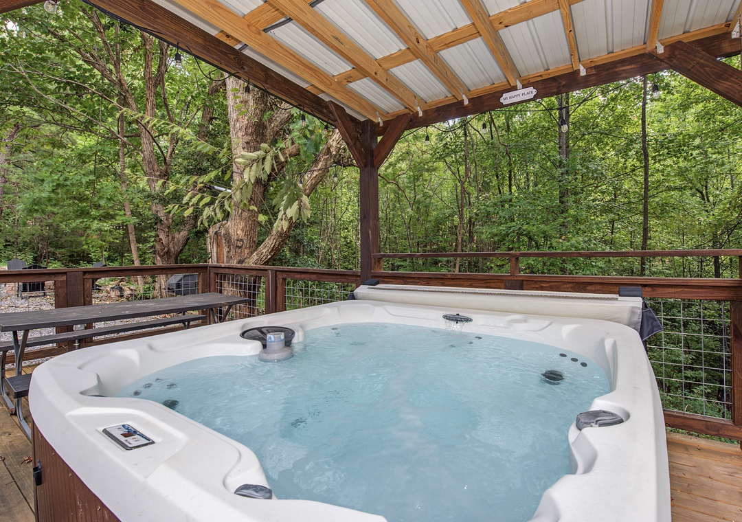 The lush forest surrounds this covered hot tub area, offering a peaceful retreat and scenic natural backdrop during your stay.