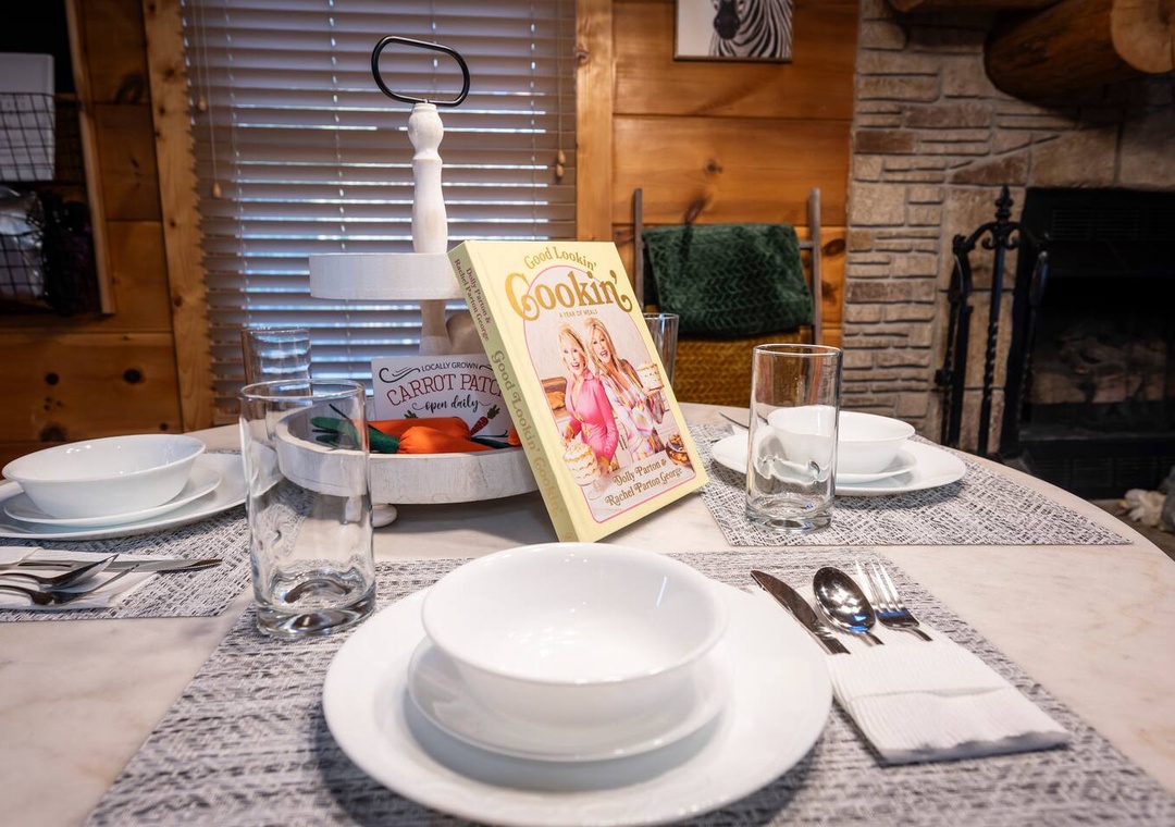 Your cozy dining table awaits, complete with charming dishware and local cookbook to inspire your culinary adventures by the warm fireplace.