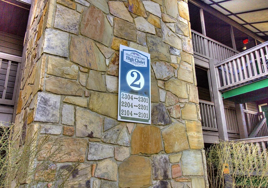 The rustic stone entrance pillar displays building directory information for this charming multi-level property.