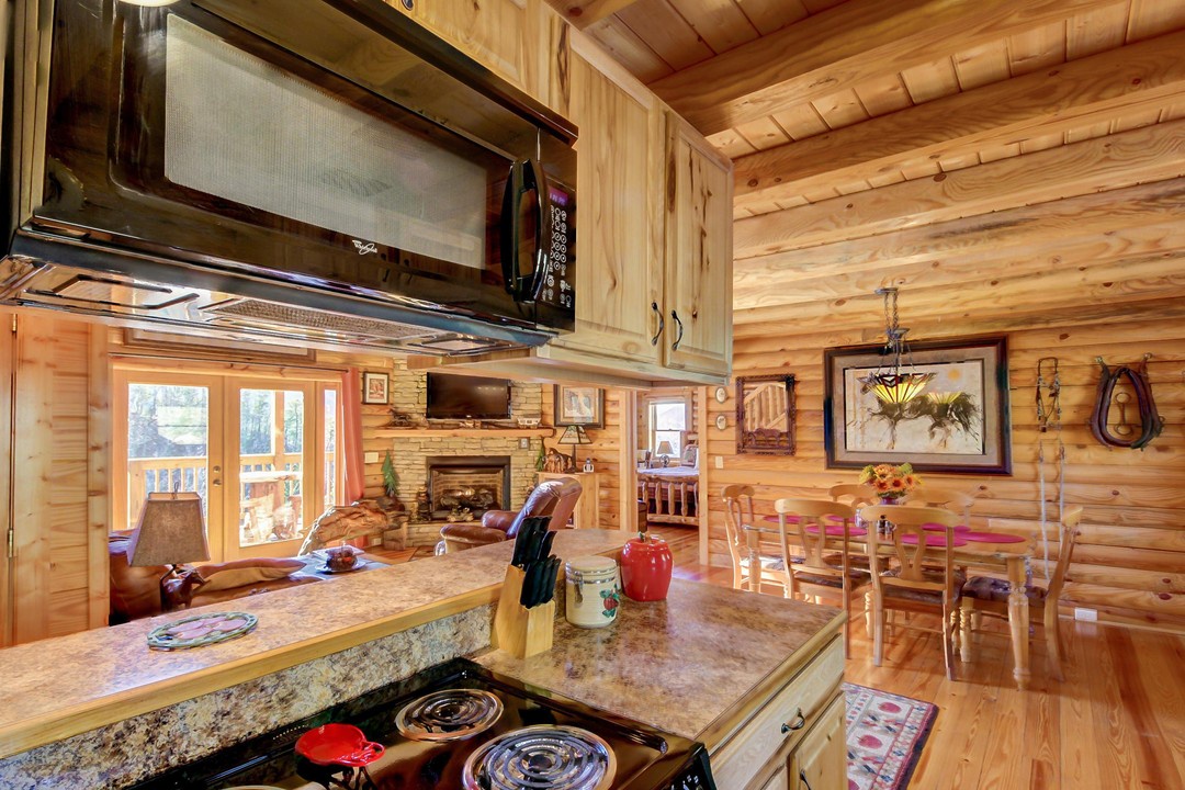 Rustic mountain elegance with warm wood, soaring ceilings, and a stone fireplace. Fully equipped kitchen opens to a cozy living space with glass doors to your private deck.