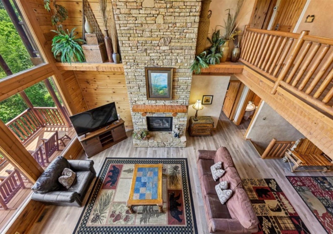 Soaring ceilings and warm wood tones embrace you in this inviting great room, where a stone fireplace anchors your mountain retreat. Sink into plush seating and let natural light pour through expansive windows.