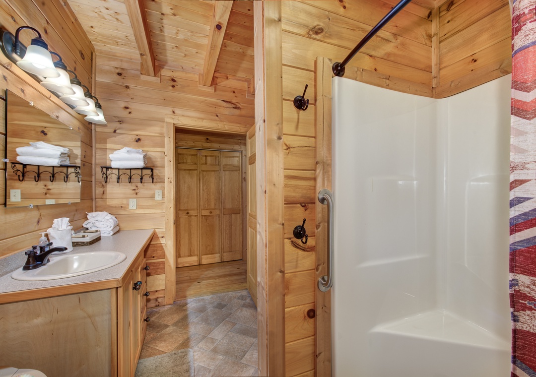 Step into your rustic cabin bathroom with warm wood walls, spacious shower, and thoughtful touches like fluffy towels and mountain charm throughout.