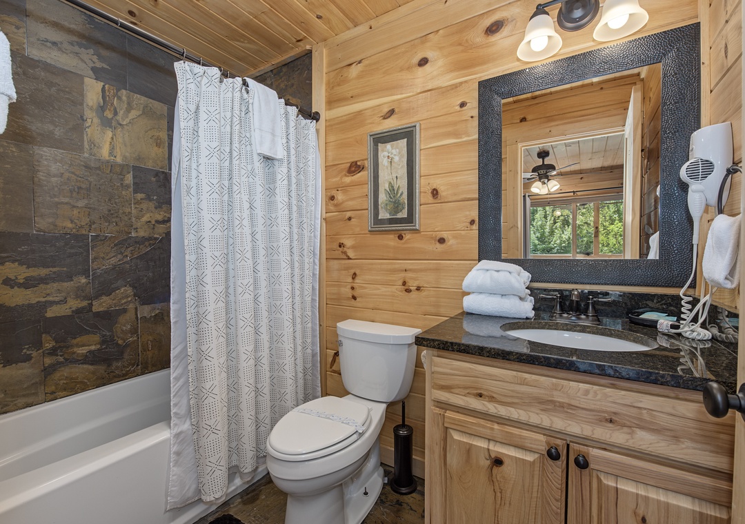 Freshen up in this charming cabin bathroom, where rustic wood paneling meets modern comfort. You'll find everything you need, from the spacious walk-in shower to plush towels waiting for you.