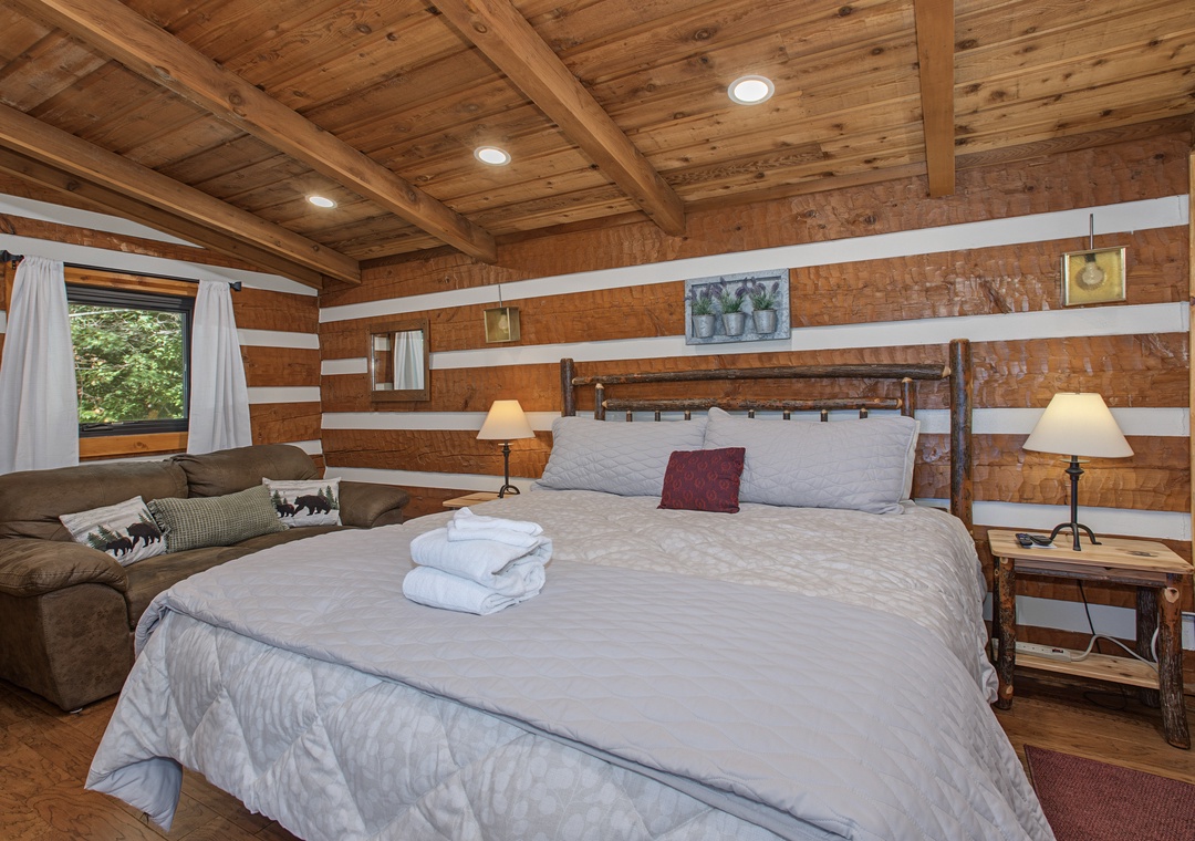 Unwind in this peaceful bedroom where rustic wood beams and crisp linens create your perfect mountain retreat. Relax under the warm glow of bedside lamps and wake to natural light streaming through your window.